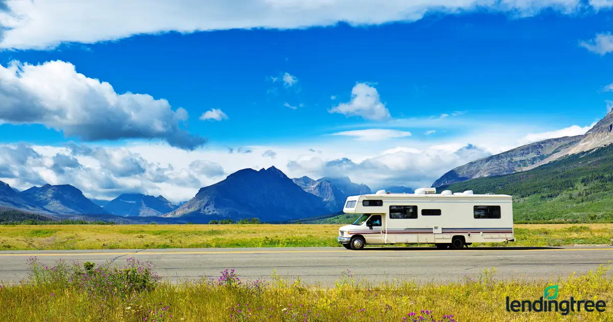 recreational vehicle on the road with mountains in the background