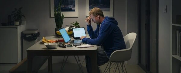 A man sitting hunched over in front of his computer stressed.