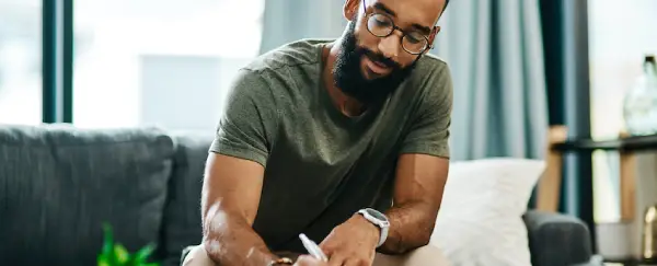 A black man signs loan paperwork.