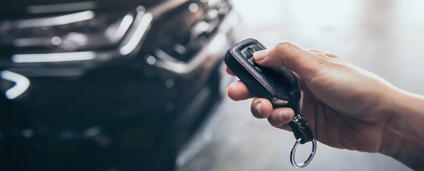 Hand presses unlock on the car remote control.