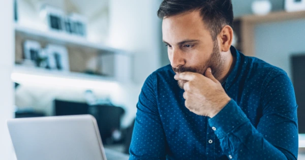 Pensive man looking at a laptop