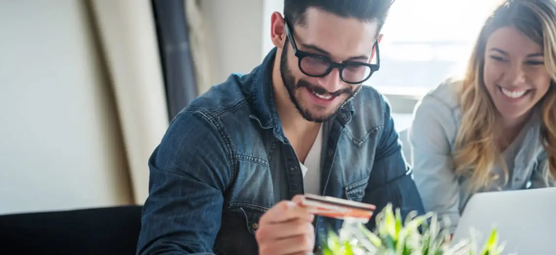 smiling man looking at credit card in his hand